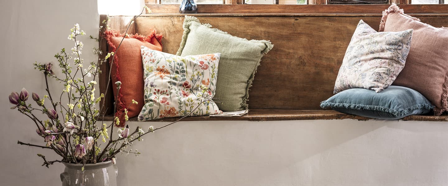 Built in wooden bench seat with an assortment of colourful and patterned throw pillows