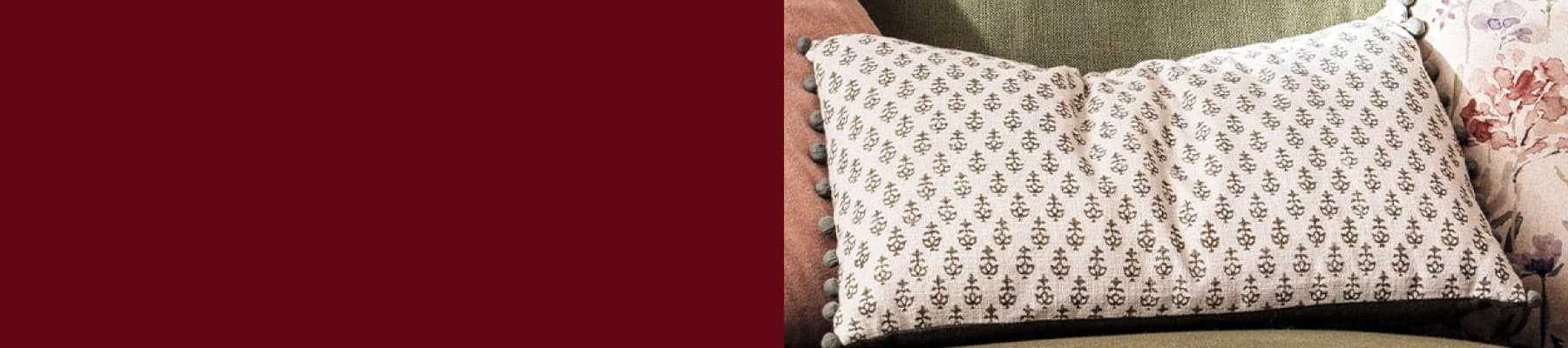 Patterned cushion with small floral designs on a green sofa, flanked by solid and floral cushions.