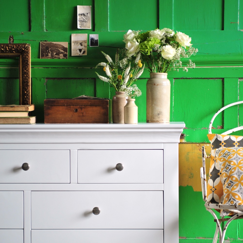white bedroom furniture, green wall, gold frames, books, vintage vases