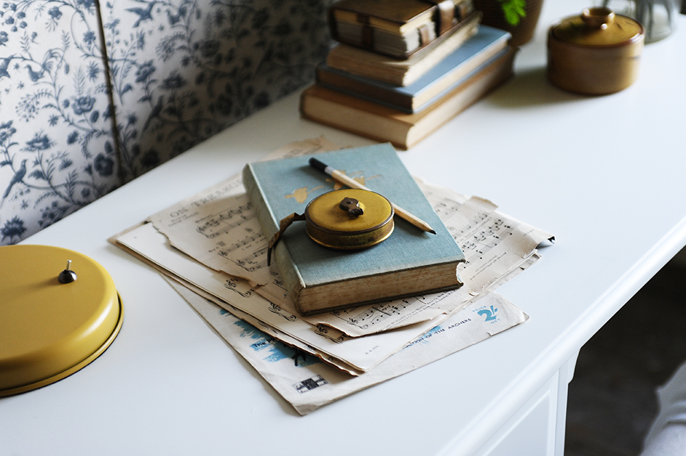 White desk, yellow, lamp, blue book, music paper